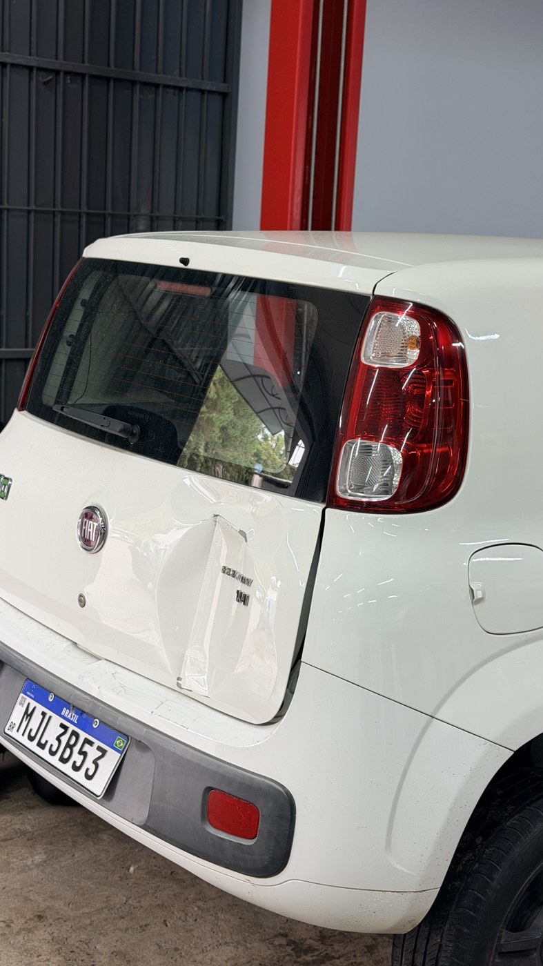 Fiat Uno branco com dano na traseira antes do reparo